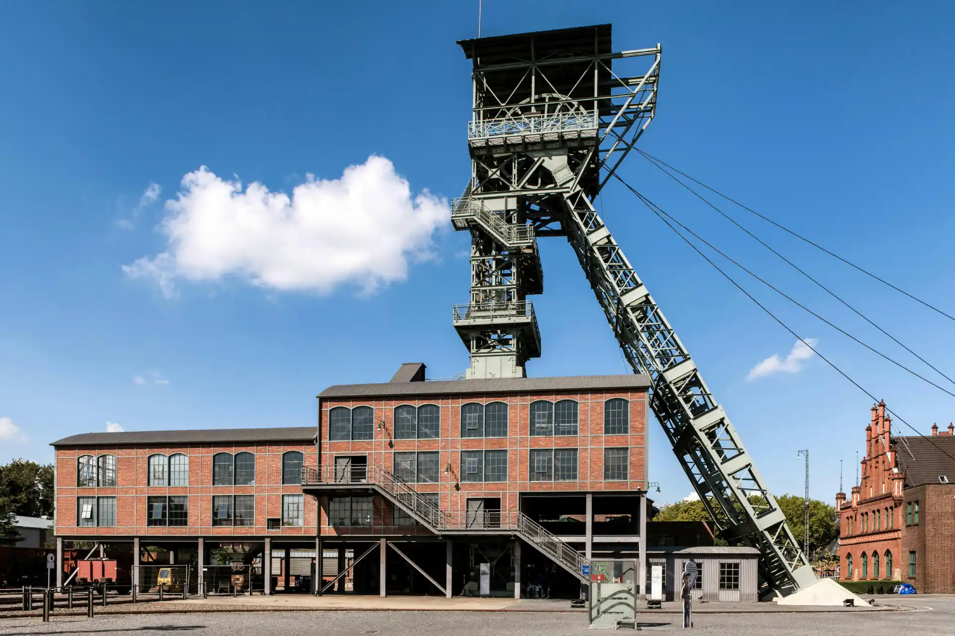 Historische deutsche Zeche mit Förderturm und Backsteingebäuden unter blauem Himmel – ein typisches Industriedenkmal des ehemaligen Steinkohlebergbaus im Ruhrgebiet.