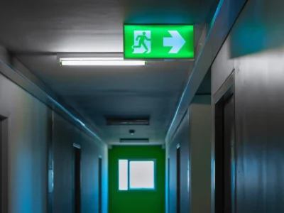Beleuchtetes Rettungswegschild mit Pfeil in einem Flur als Orientierung für Flucht- und Rettungswege