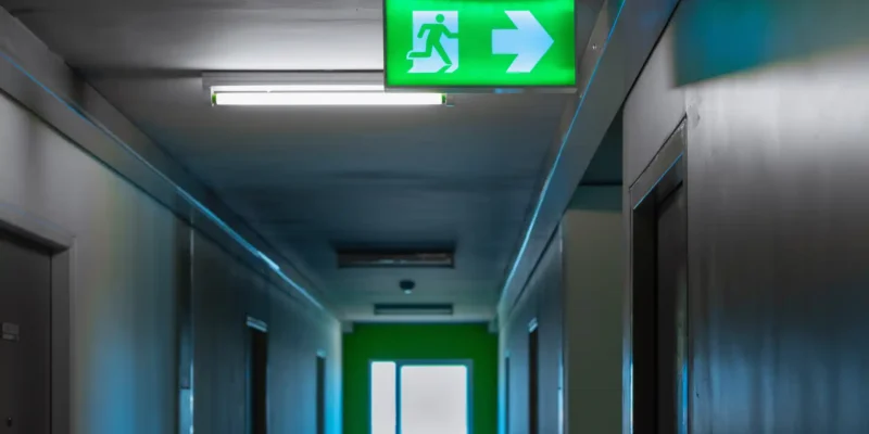 Beleuchtetes Rettungswegschild mit Pfeil in einem Flur als Orientierung für Flucht- und Rettungswege