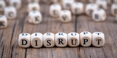 Holzwürfel bilden das Wort Disrupt – eine visuelle Darstellung von Disruption und radikalen Veränderungen in Wirtschaft und Technologie.
